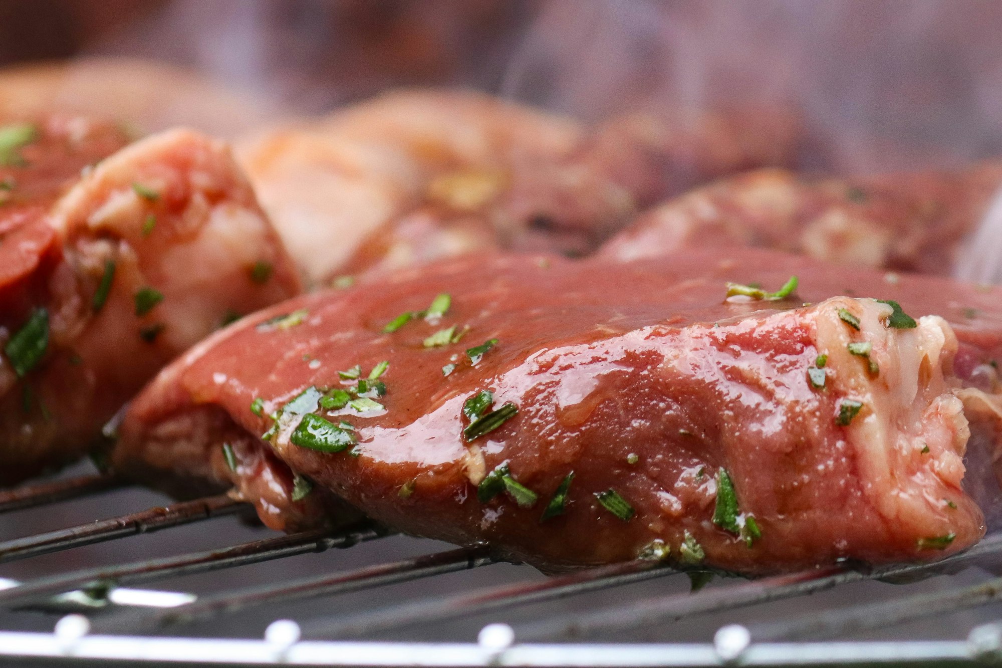 A juicy raw rump steak cooking on a barbecue.