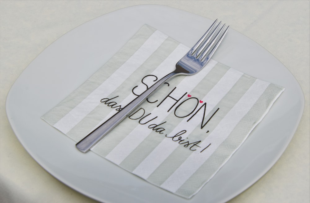 tenedor y cuchillo plateados sobre plato redondo blanco