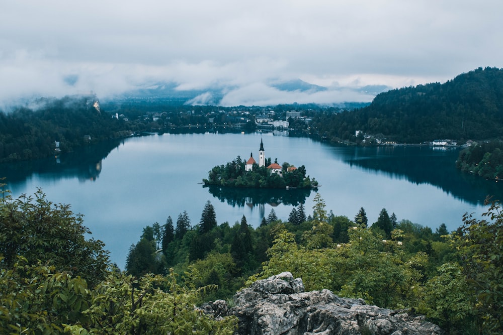 green trees near lake under white clouds during daytime