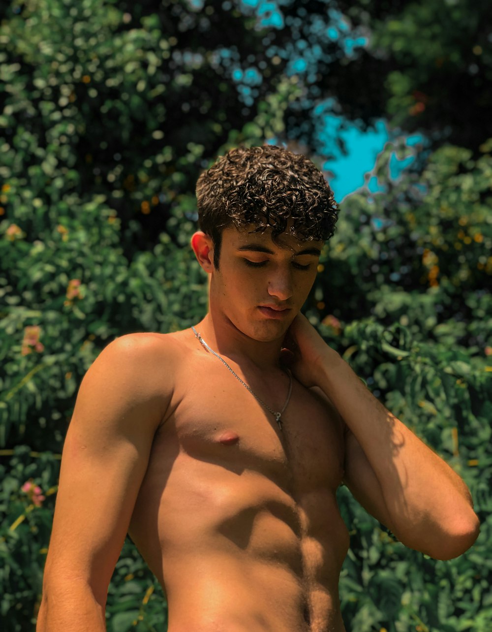 topless man standing near green plants during daytime