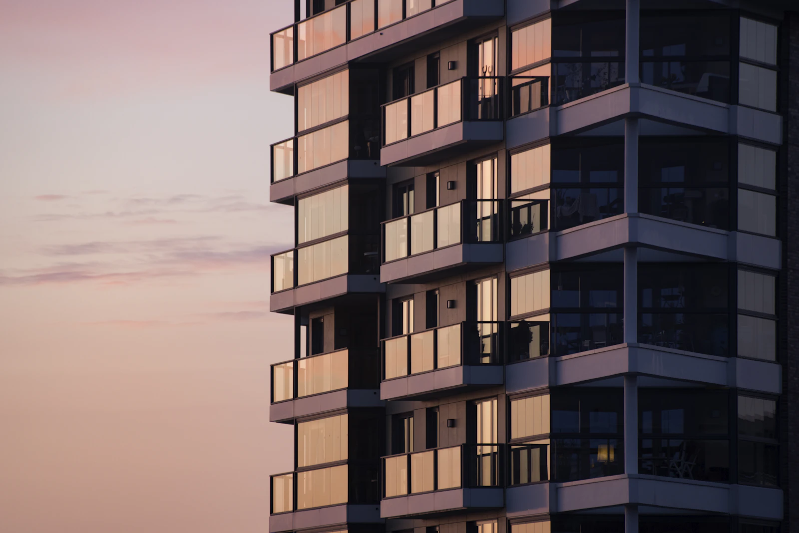 Modern apartment building with glass balconies at dusk