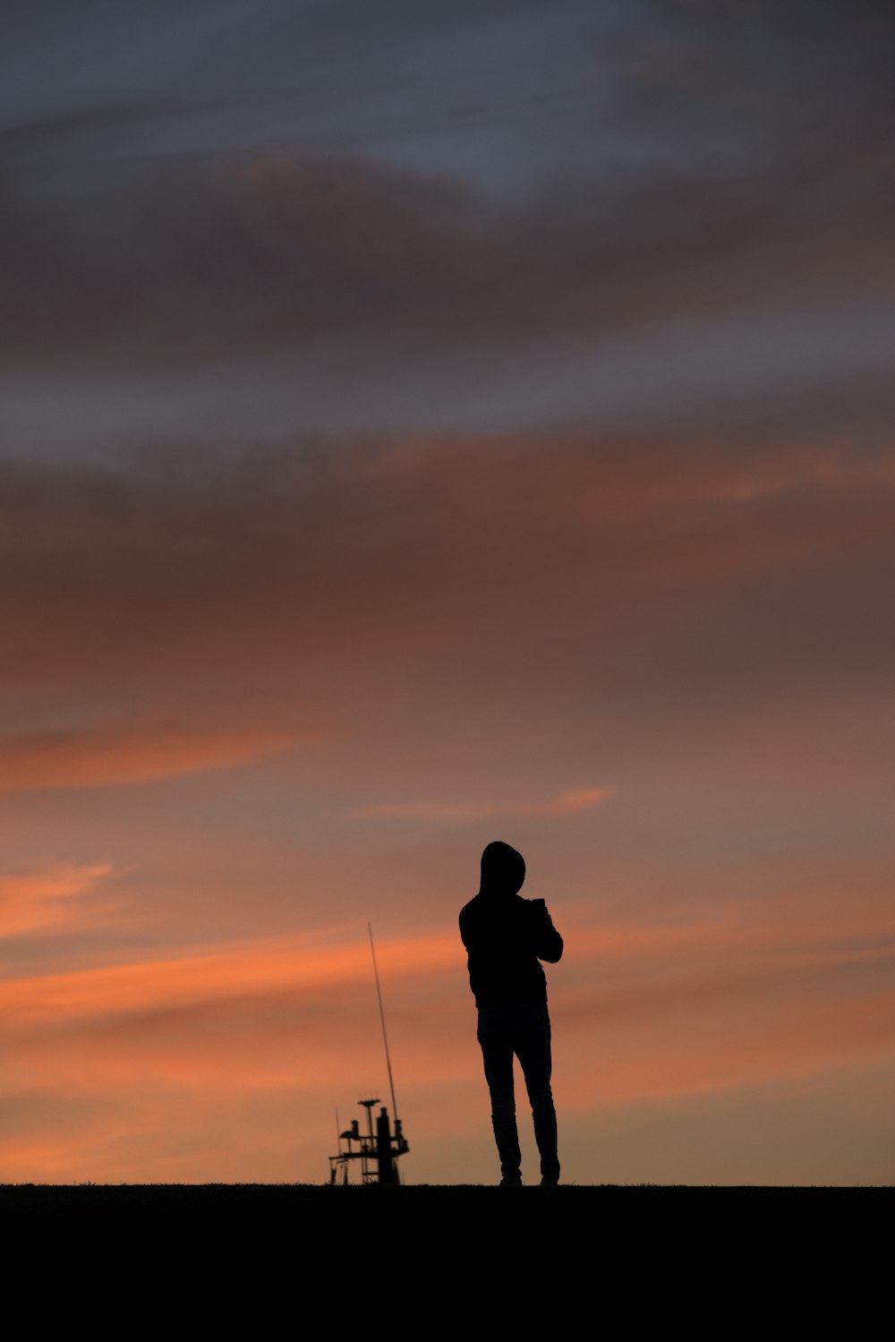 Eine Person, die bei Sonnenuntergang auf einem Hügel steht