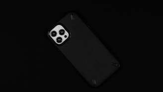 A smartphone with a prominent camera module featuring three lenses against a dark background.