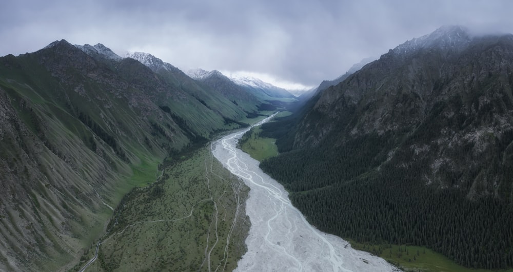 green mountains and river under white clouds and blue sky during daytime