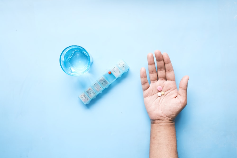 person holding pink and white medicine pill