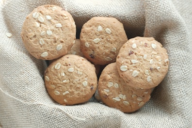 Golden oatmeal cookies with raisins and a sprinkle of cinnamon on a rustic wooden table.