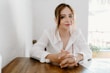 woman in white blazer sitting by the table