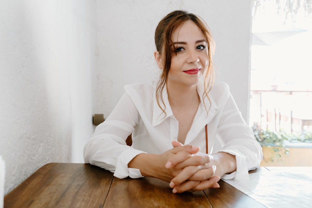 woman in white blazer sitting by the table