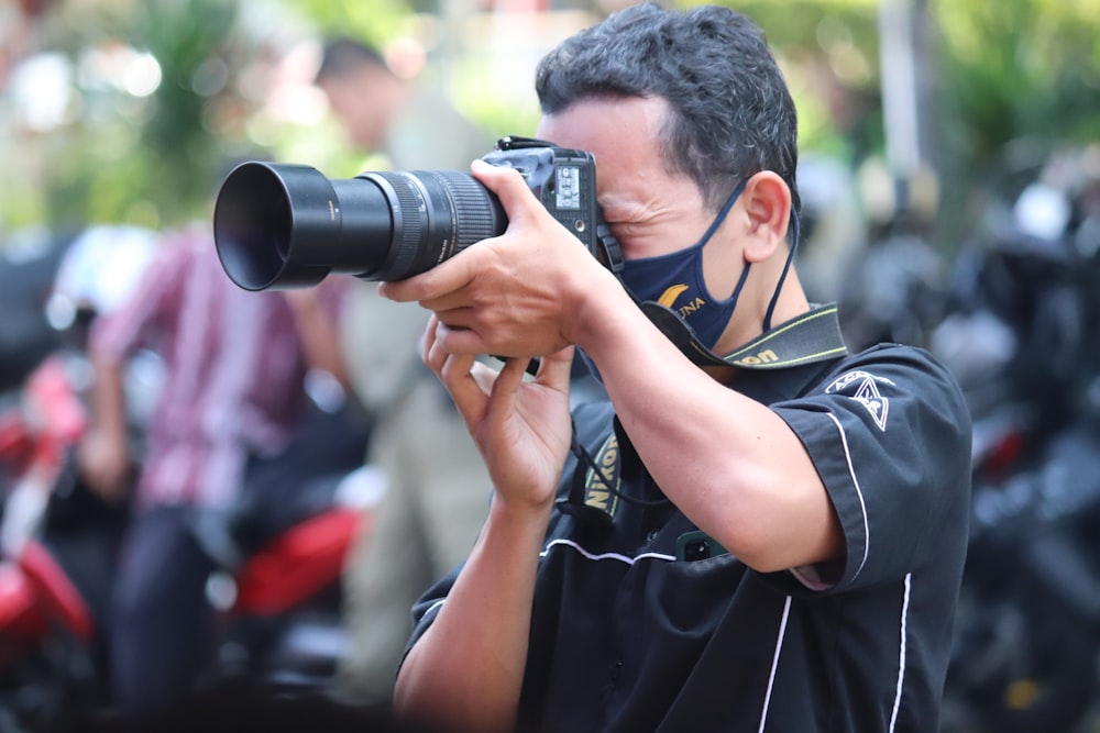man in black and yellow polo shirt holding black dslr camera