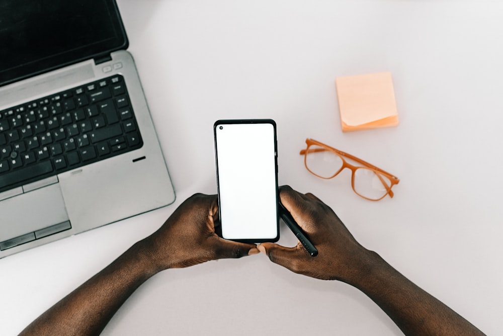 person holding white smartphone on white table