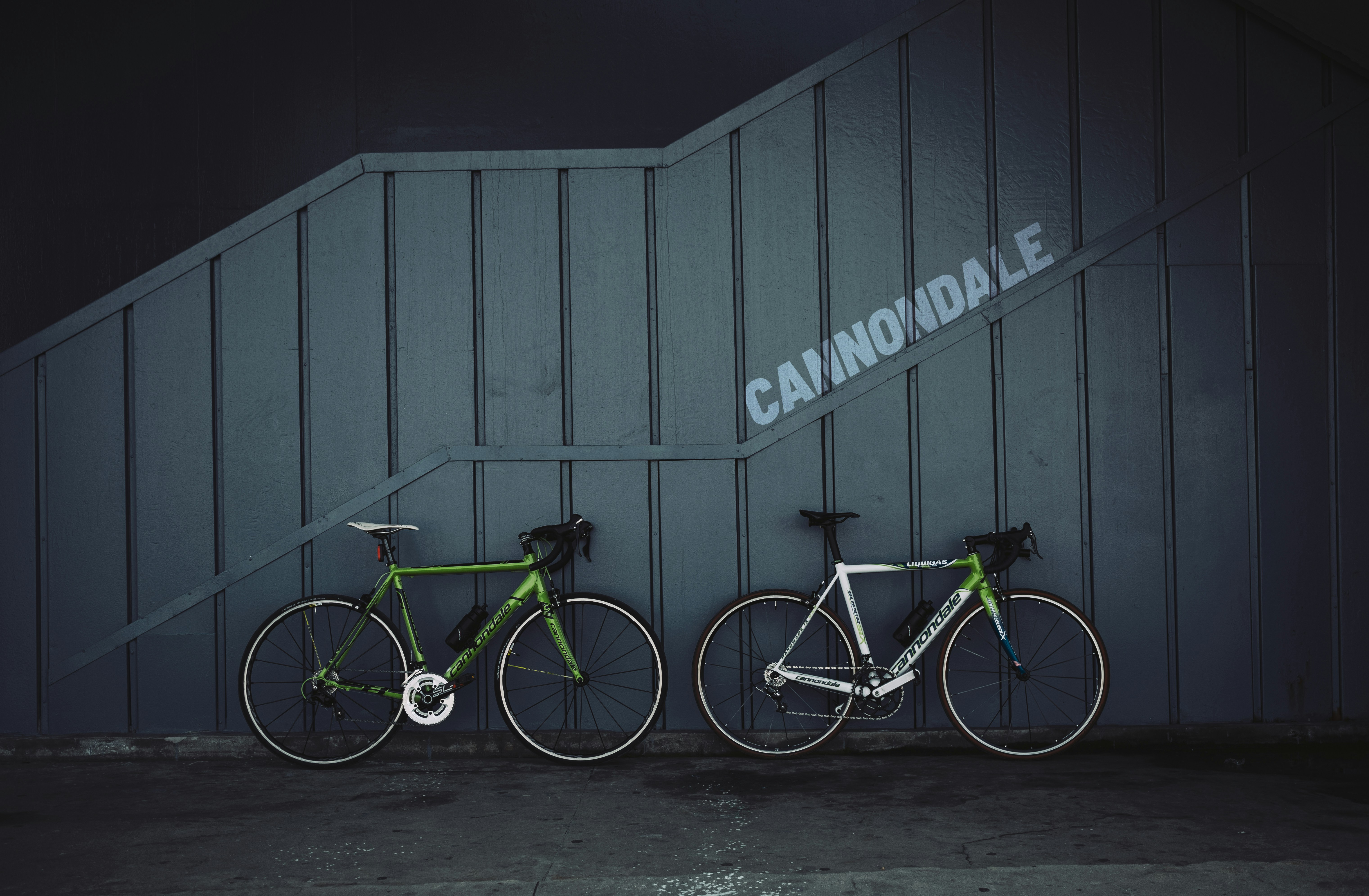 green and black road bike beside gray wooden wall