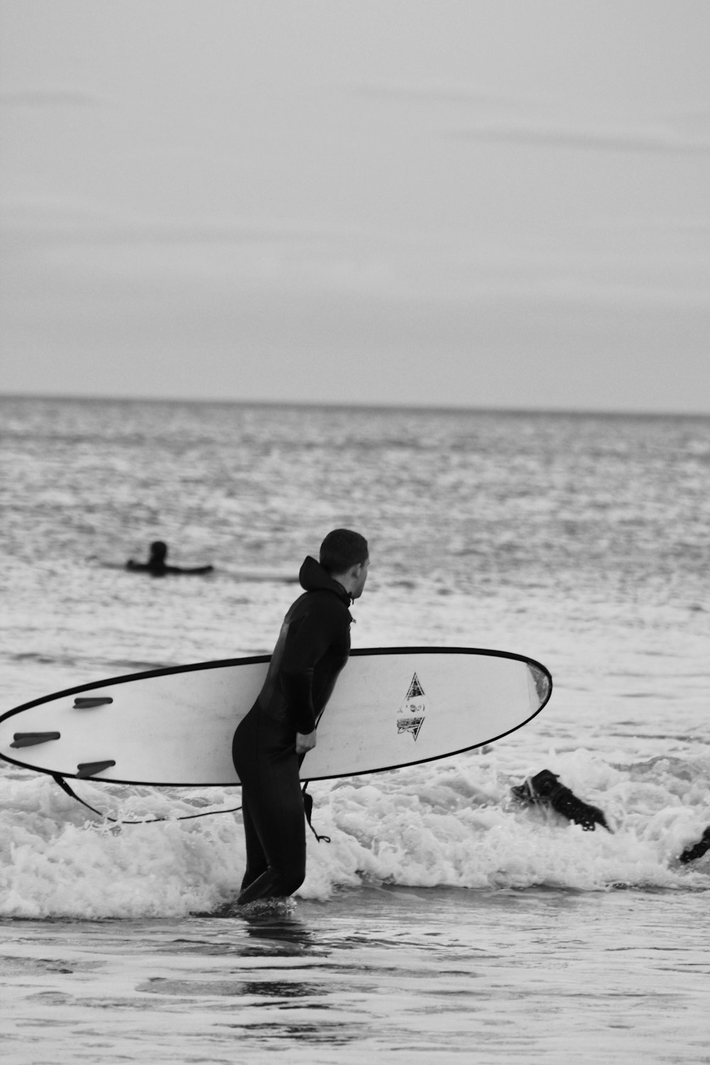 hombre con traje de neopreno negro sosteniendo una tabla de surf en la playa