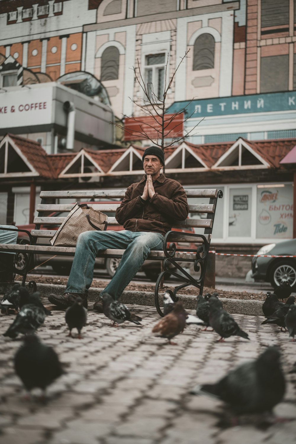 man in brown jacket sitting on brown wooden bench during daytime