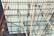 Workers are perched atop a complex network of scaffolding beams under a bright sky, engaging in construction or maintenance tasks.