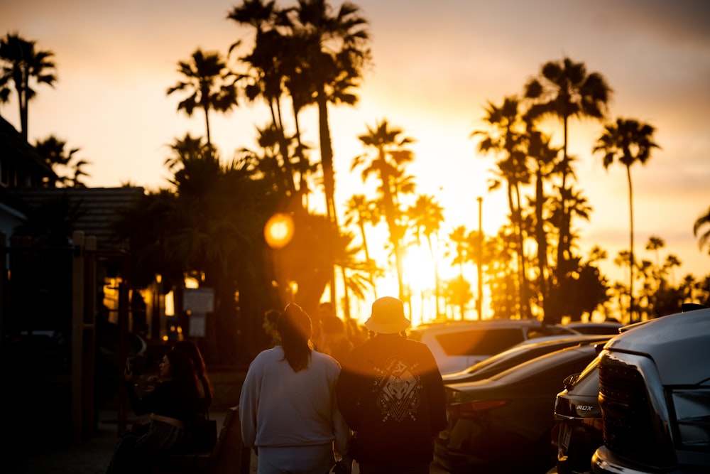 man in white shirt standing near palm trees during sunset