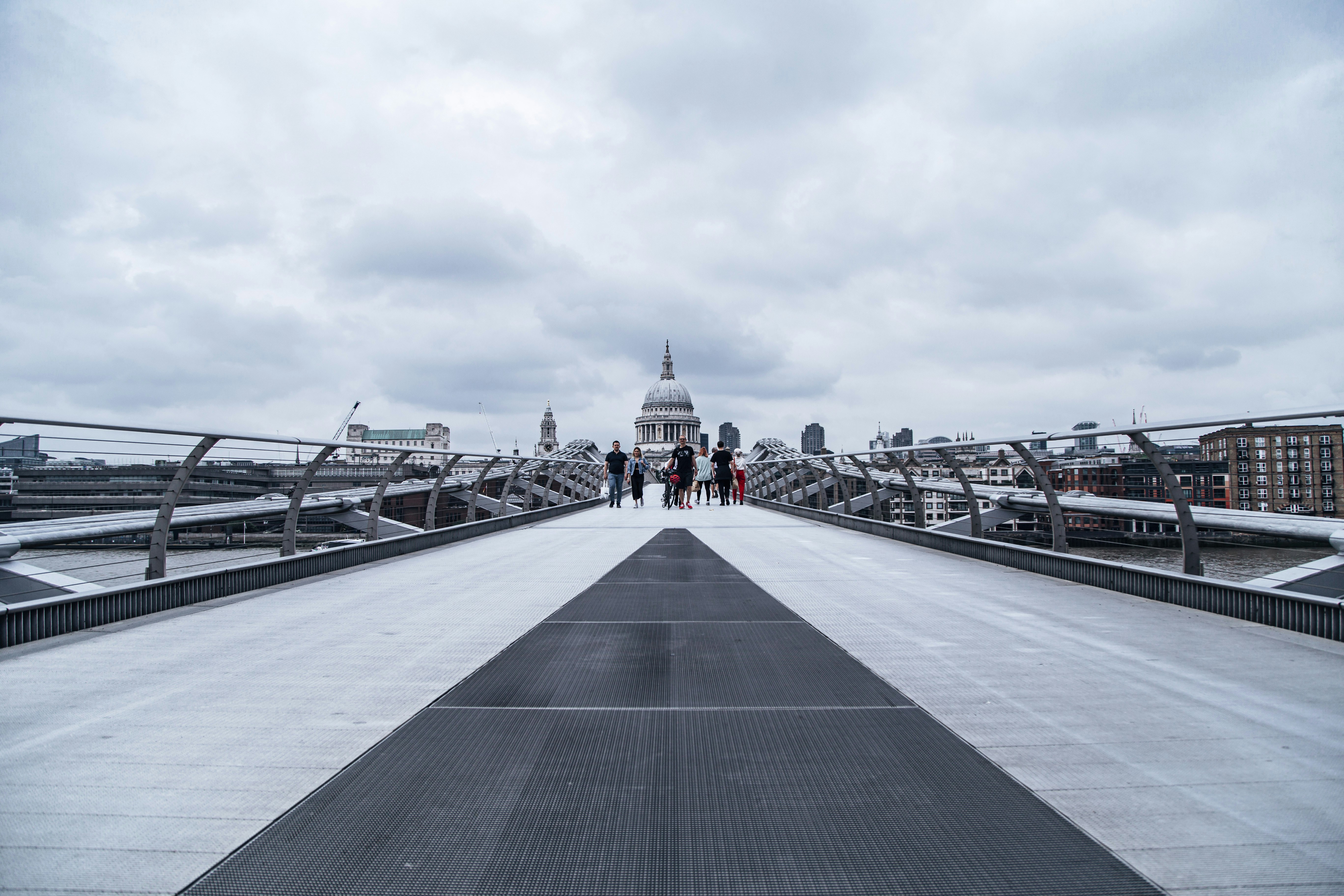people walking on gray concrete bridge under gray sky during daytime