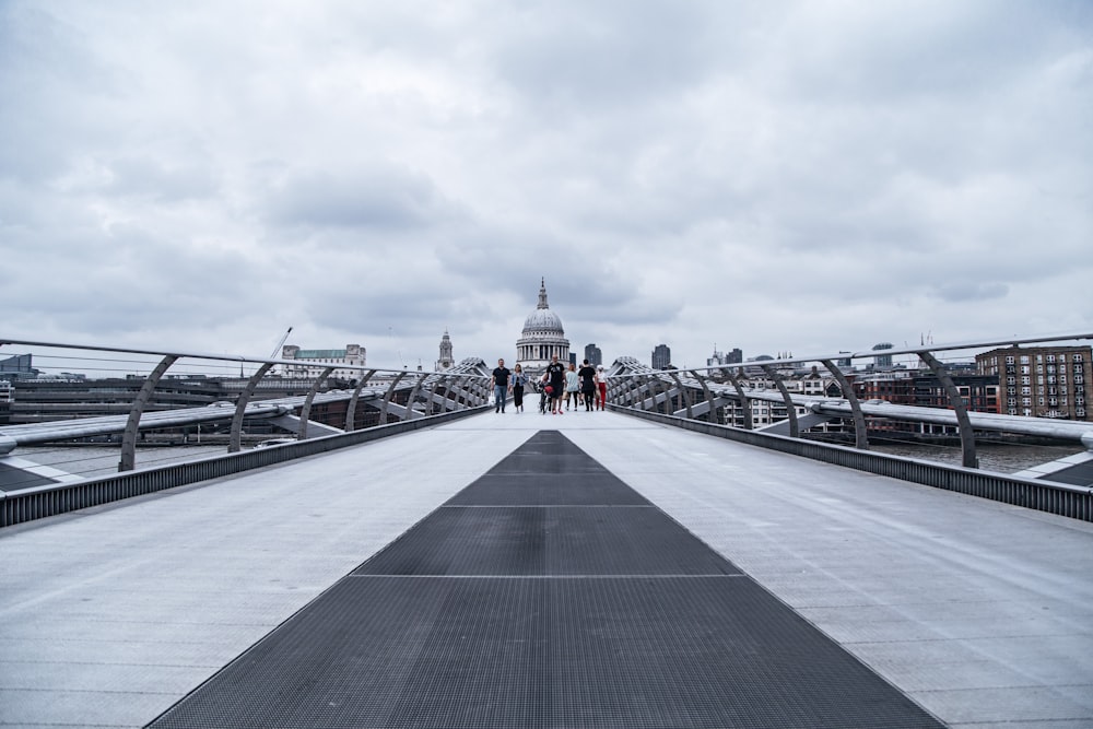 people walking on gray concrete bridge under gray sky during daytime