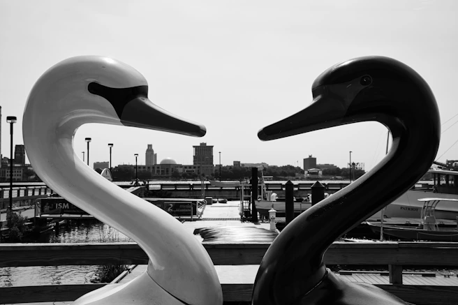 grayscale photo of two person walking on the bridge