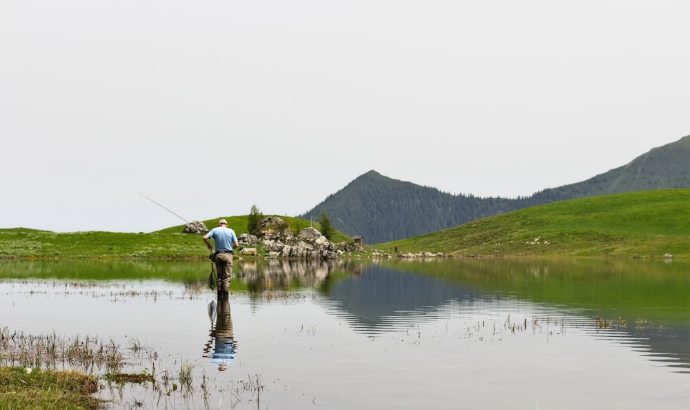 man in white shirt and black shorts fishing on lake during daytime