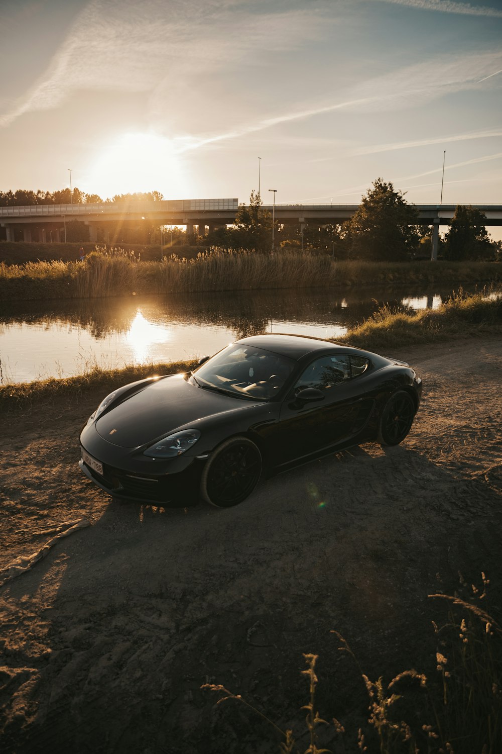 black porsche 911 parked on road near lake during daytime