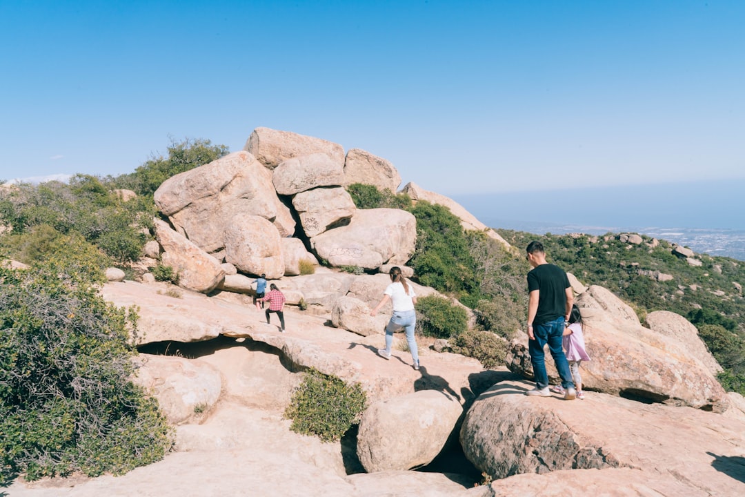 man in black t-shirt and gray shorts standing on gray rock during daytime