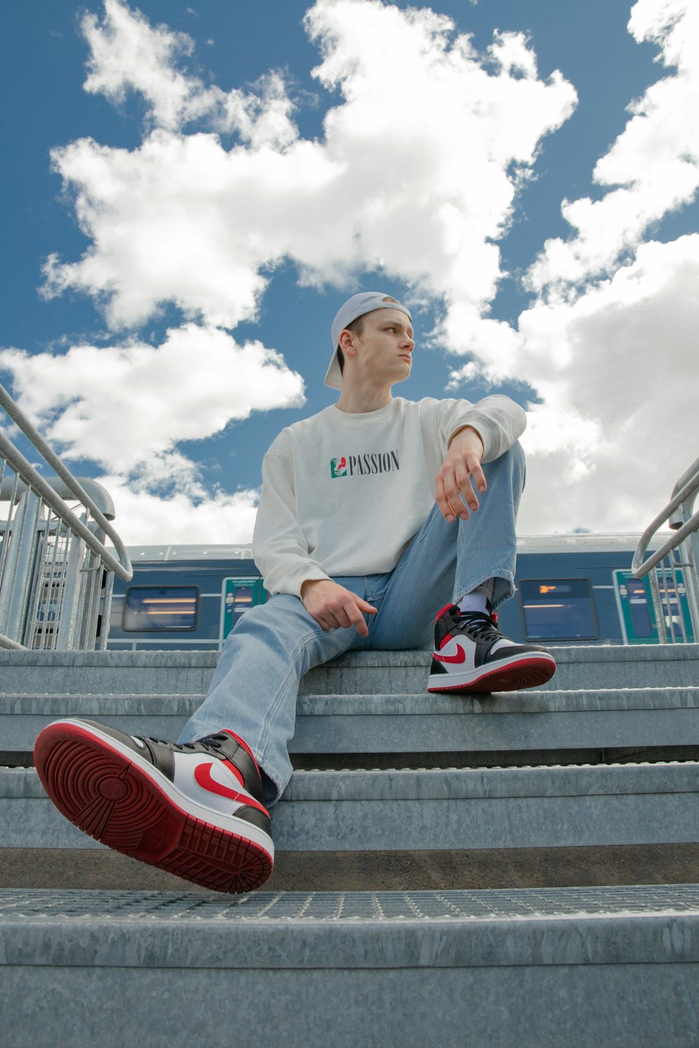 man in white sweater sitting on brown wooden bench during daytime