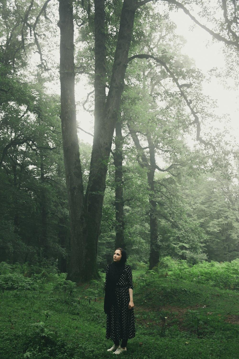 a woman standing in the middle of a forest