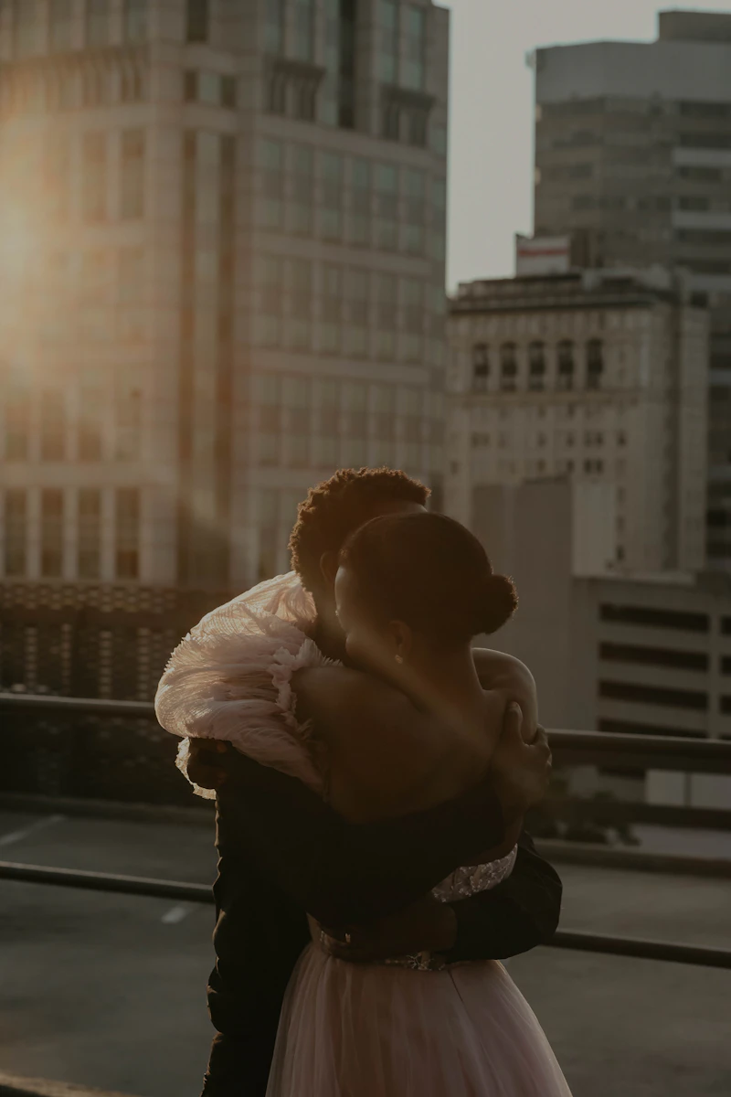 Bride in a floral veil kissing the groom on a rooftop