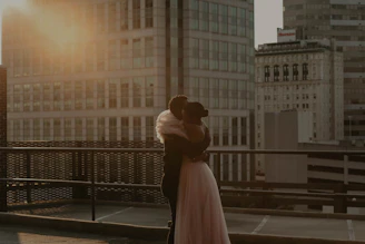 A sunlit candid moment of a couple laughing together on a terracotta-colored rooftop at golden hour.