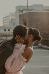 man in black leather jacket kissing woman in pink dress