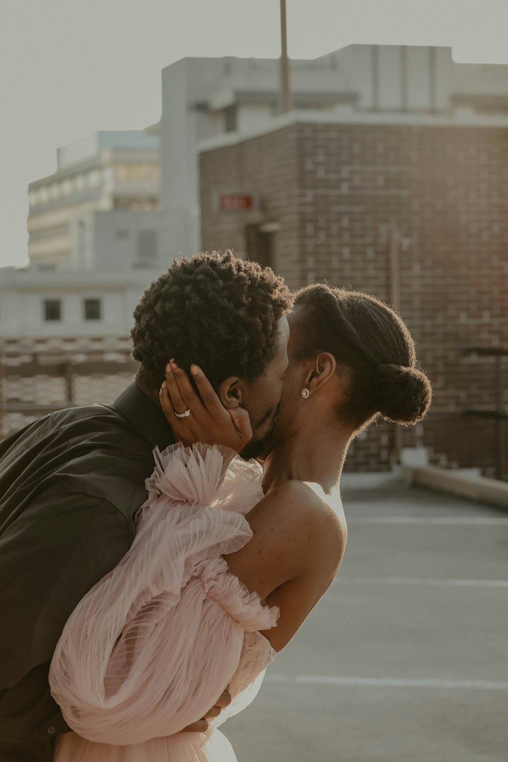 homem na jaqueta de couro preta beijando a mulher no vestido rosa