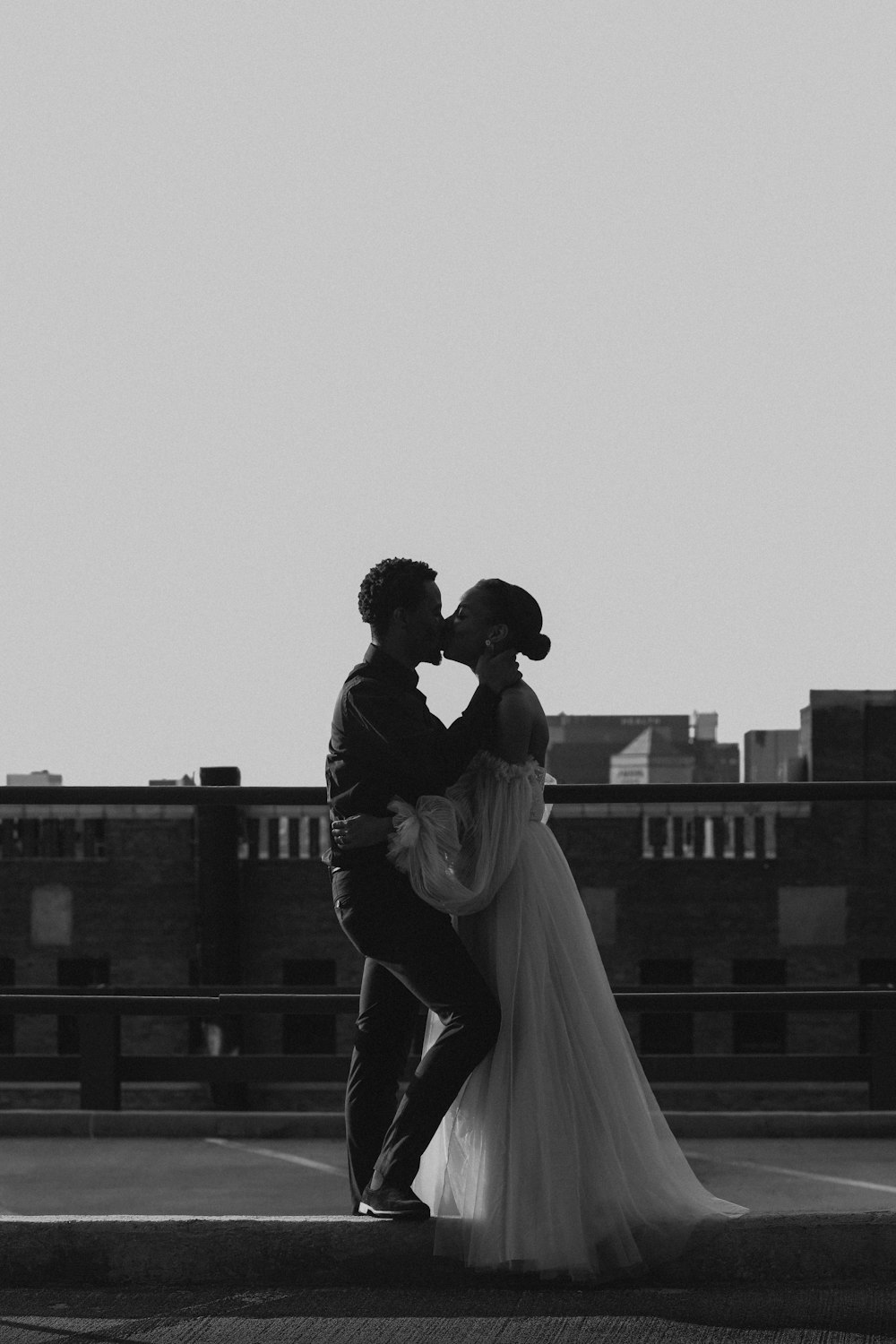 man and woman kissing on top of building
