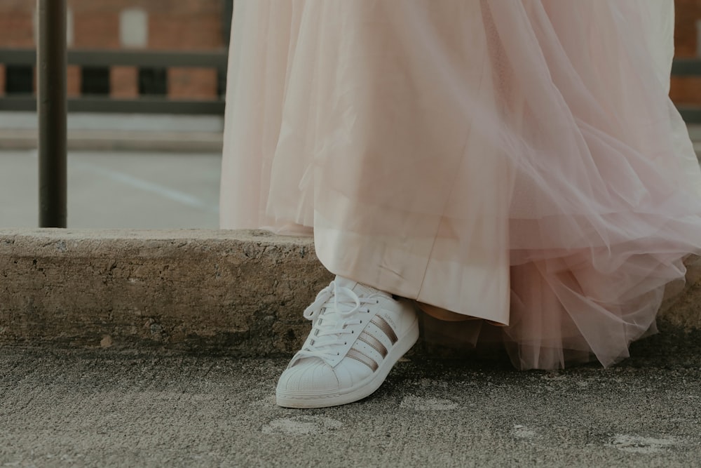 person in white sneakers standing on gray concrete floor