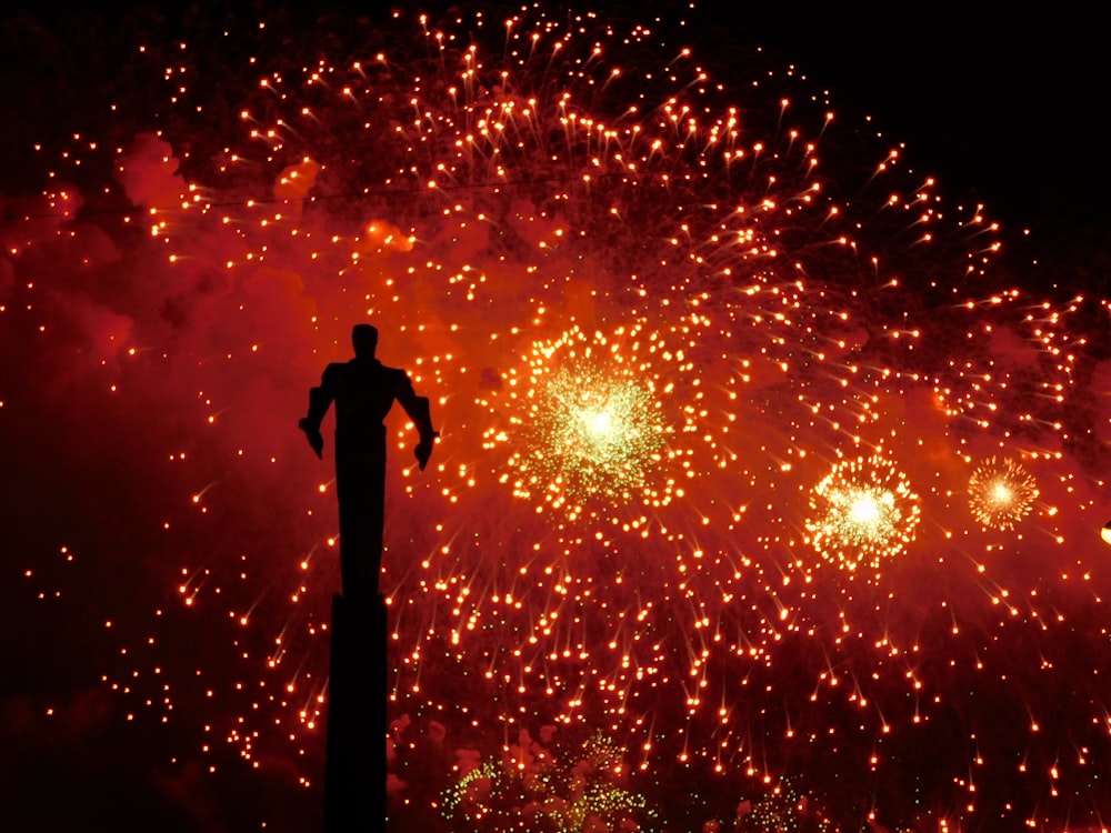 silhueta do homem em pé sob fogos de artifício durante a noite