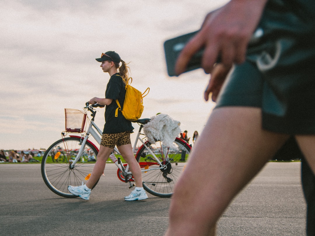 woman in yellow shirt and black shorts riding on bicycle during daytime