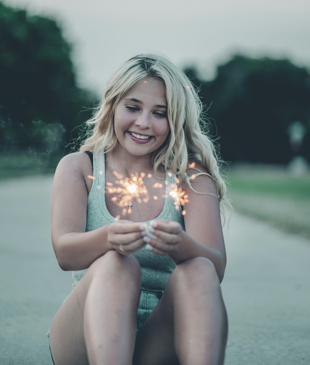 woman in gray tank top holding white and yellow flower