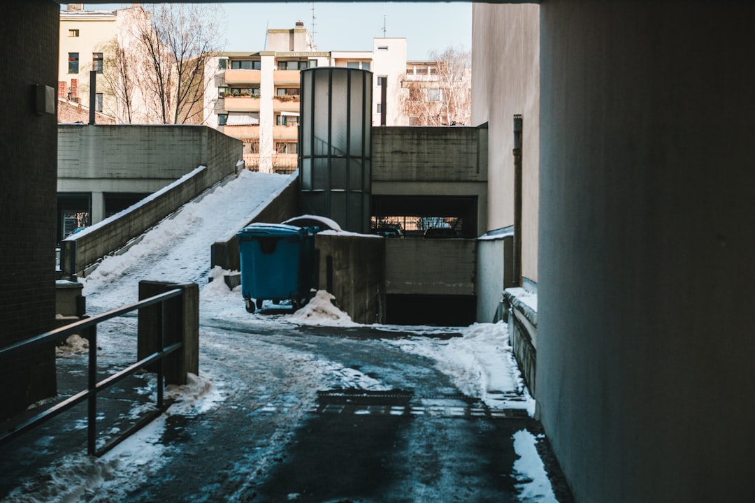 blue trash bin beside white wall