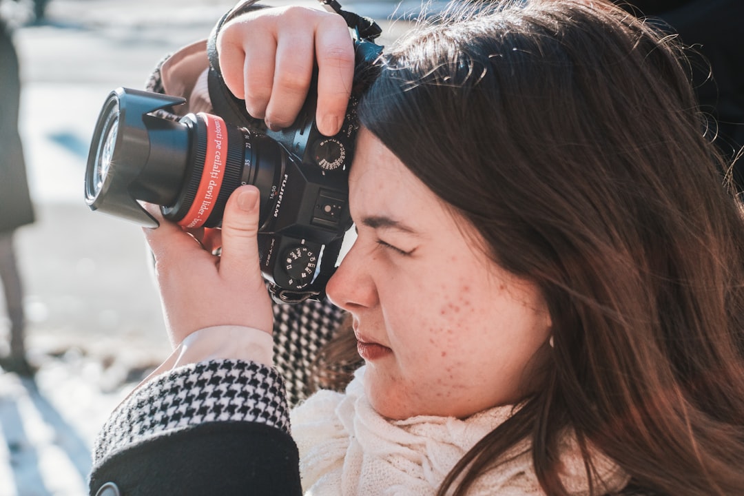 woman in black and white shirt holding black dslr camera