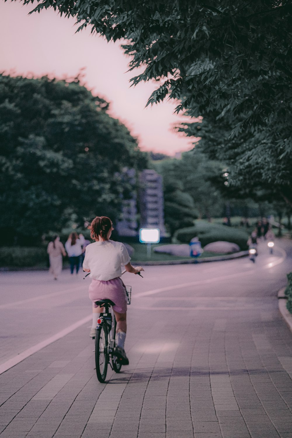 낮 동안 도로에서 자전거를 타는 분홍색 재킷을 입은 소녀