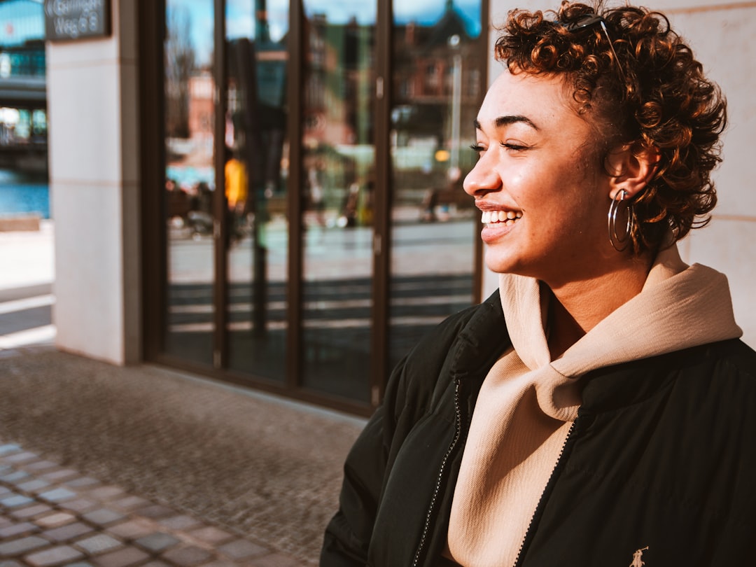 woman in black jacket standing on sidewalk during daytime