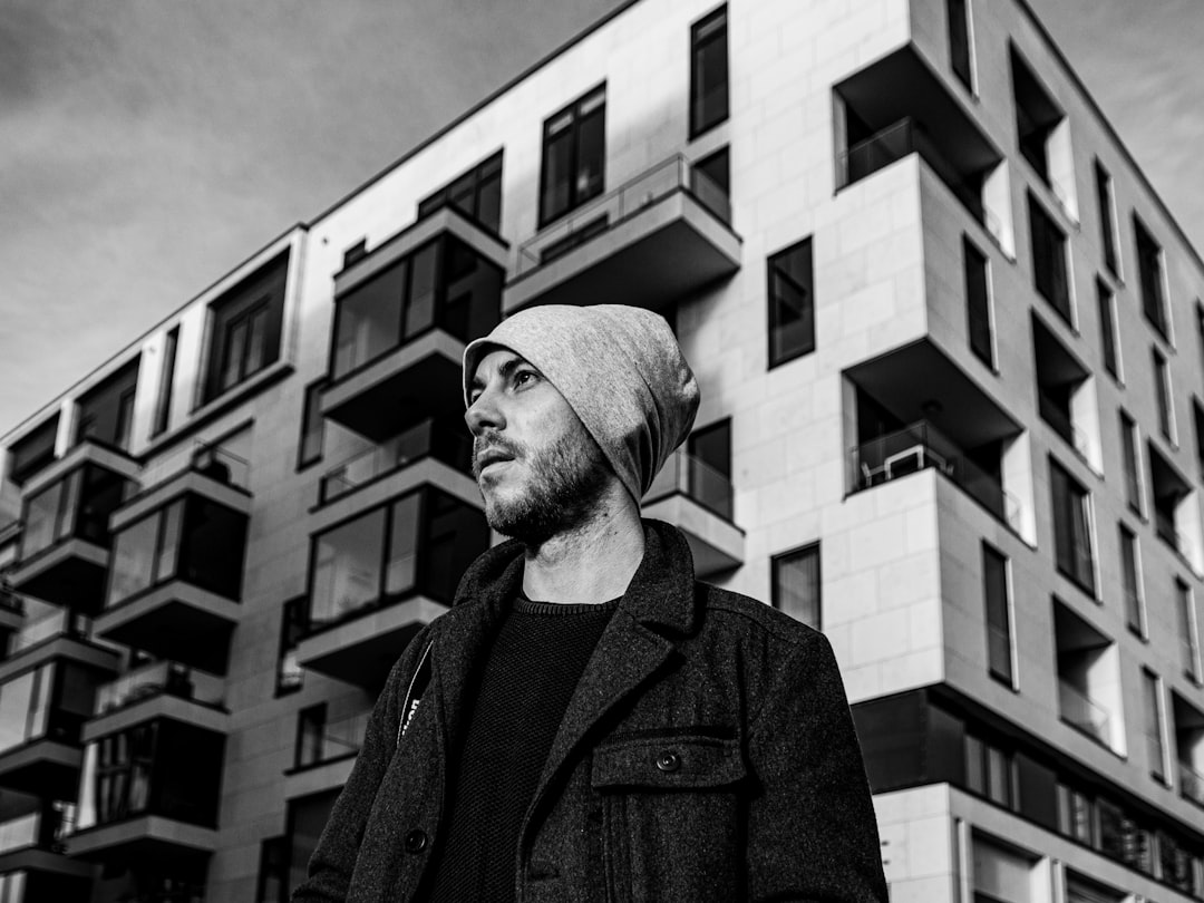 grayscale photo of man in black coat and knit cap