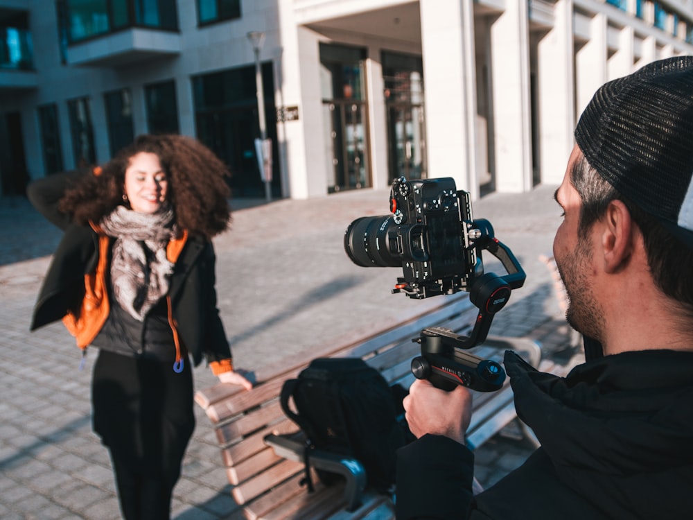 man in black jacket holding black dslr camera