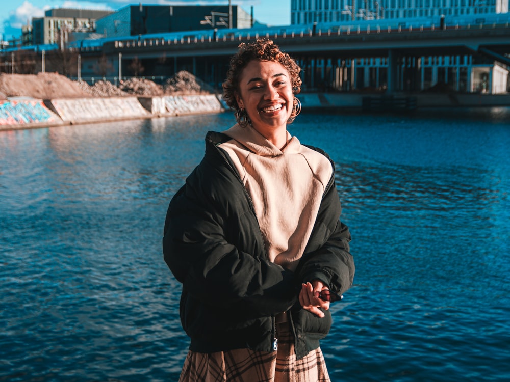 woman in black jacket standing near body of water during daytime