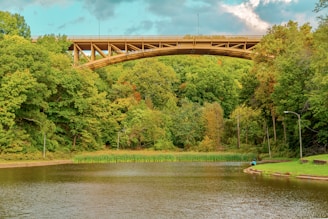 people riding on blue boat on river under bridge during daytime
