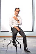 man in white dress shirt and black pants sitting on black rolling chair