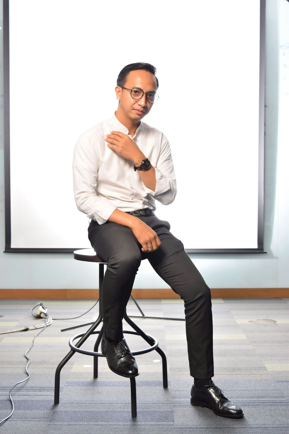 man in white dress shirt and black pants sitting on black rolling chair