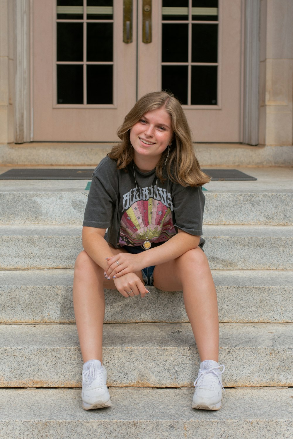 woman in black crew neck t-shirt sitting on gray concrete stairs