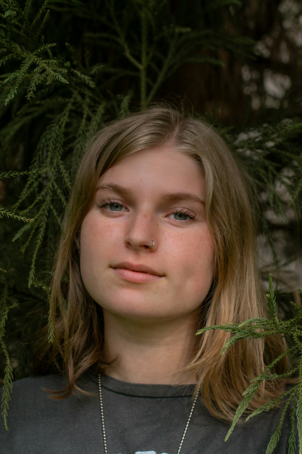 woman in green shirt standing near green plant