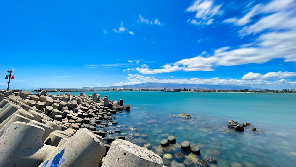 gray rocks on sea shore under blue sky during daytime