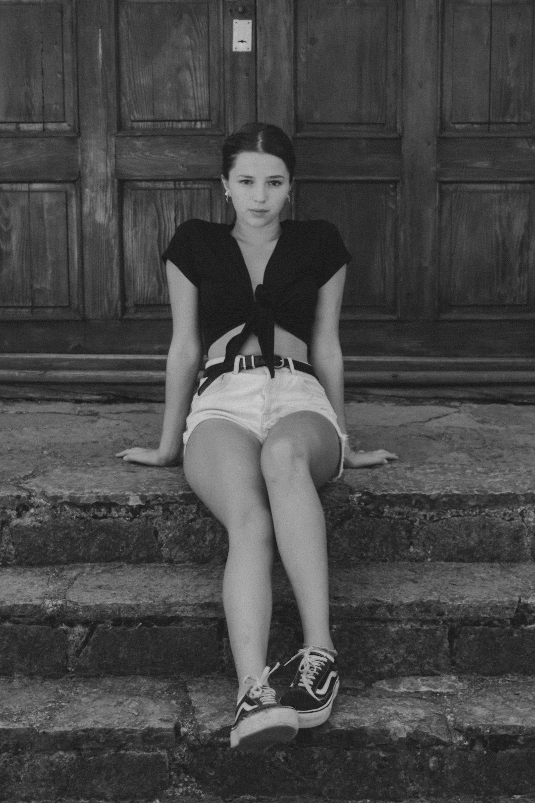 woman in black shirt and white skirt sitting on concrete stairs